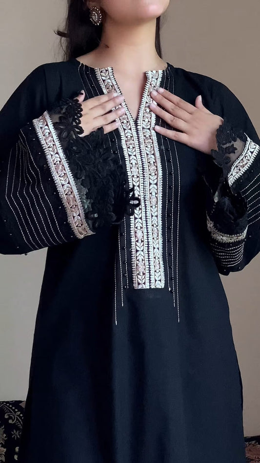 Black dress with intricate white embroidery on a plain background